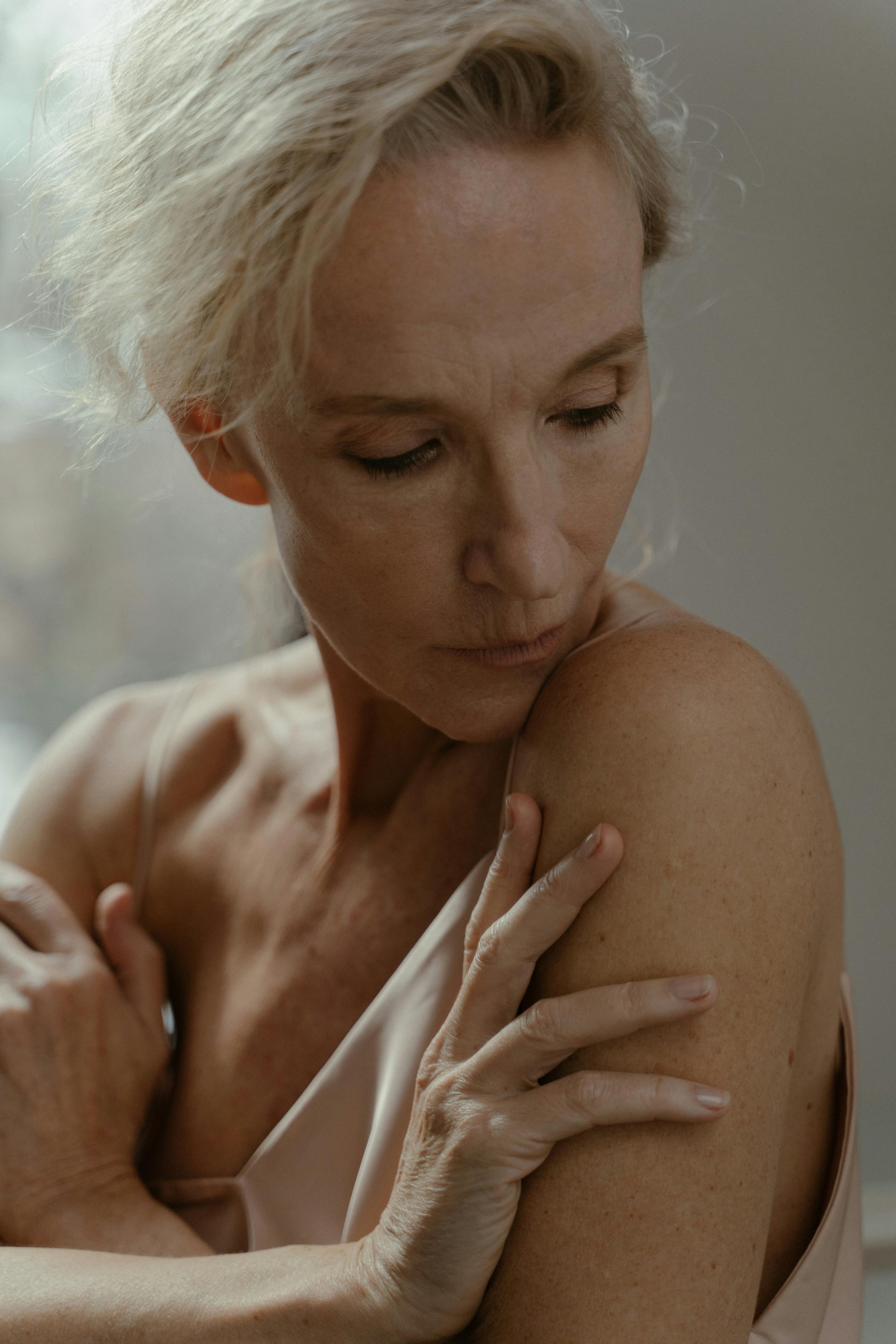 a portrait of an elderly woman touching her skin