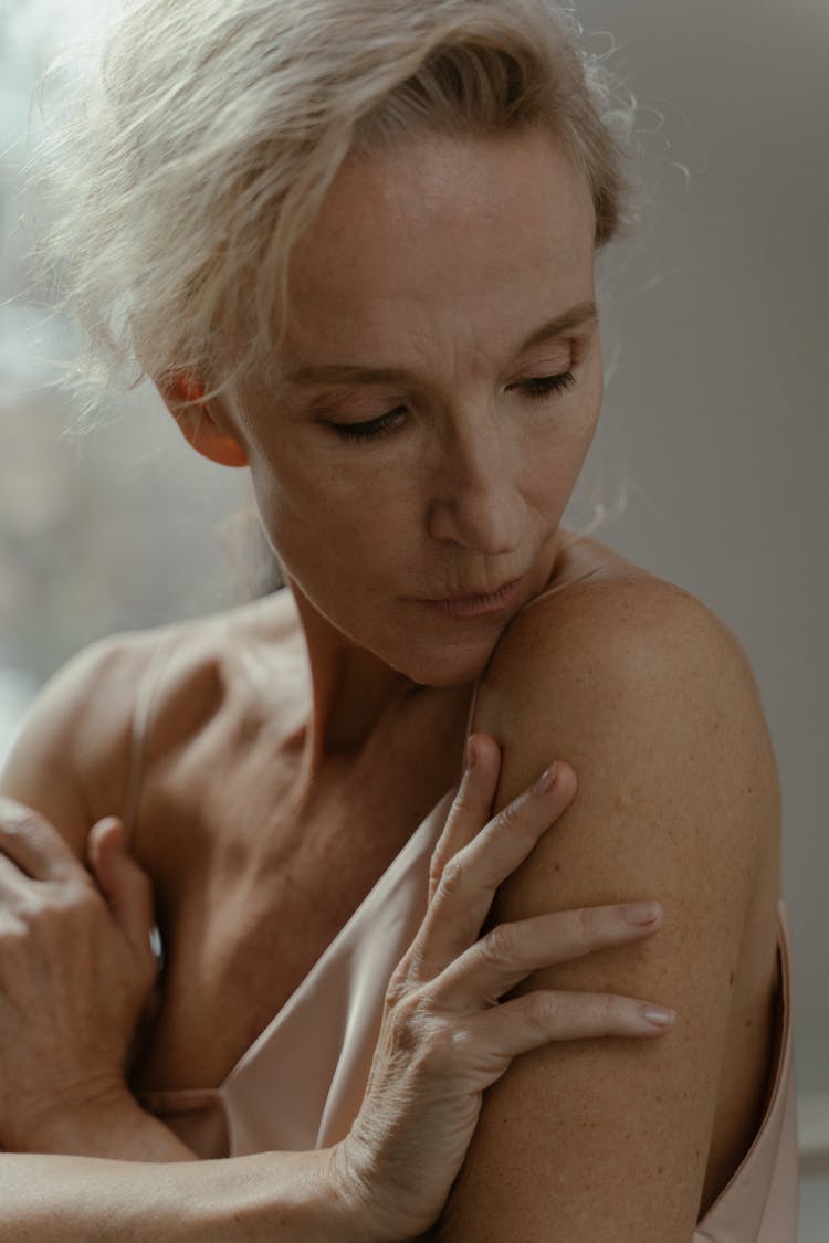  A Portrait Of An Elderly Woman Touching Her Skin