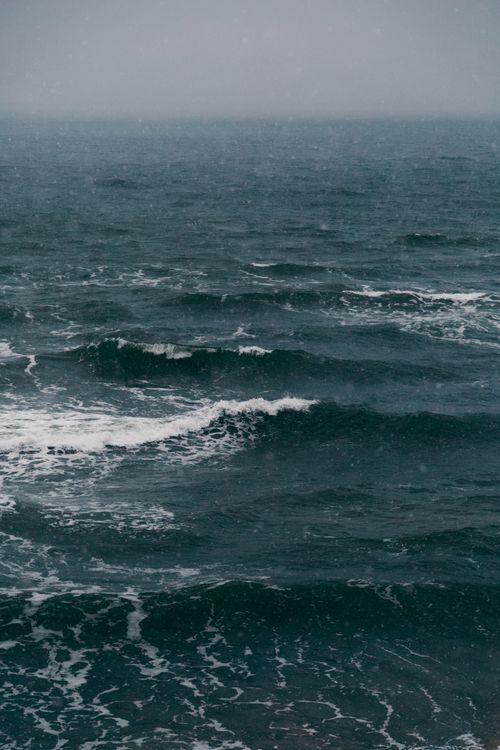 Free A dramatic and moody view of ocean waves under a foggy sky, perfect for nature-themed projects. Stock Photo
