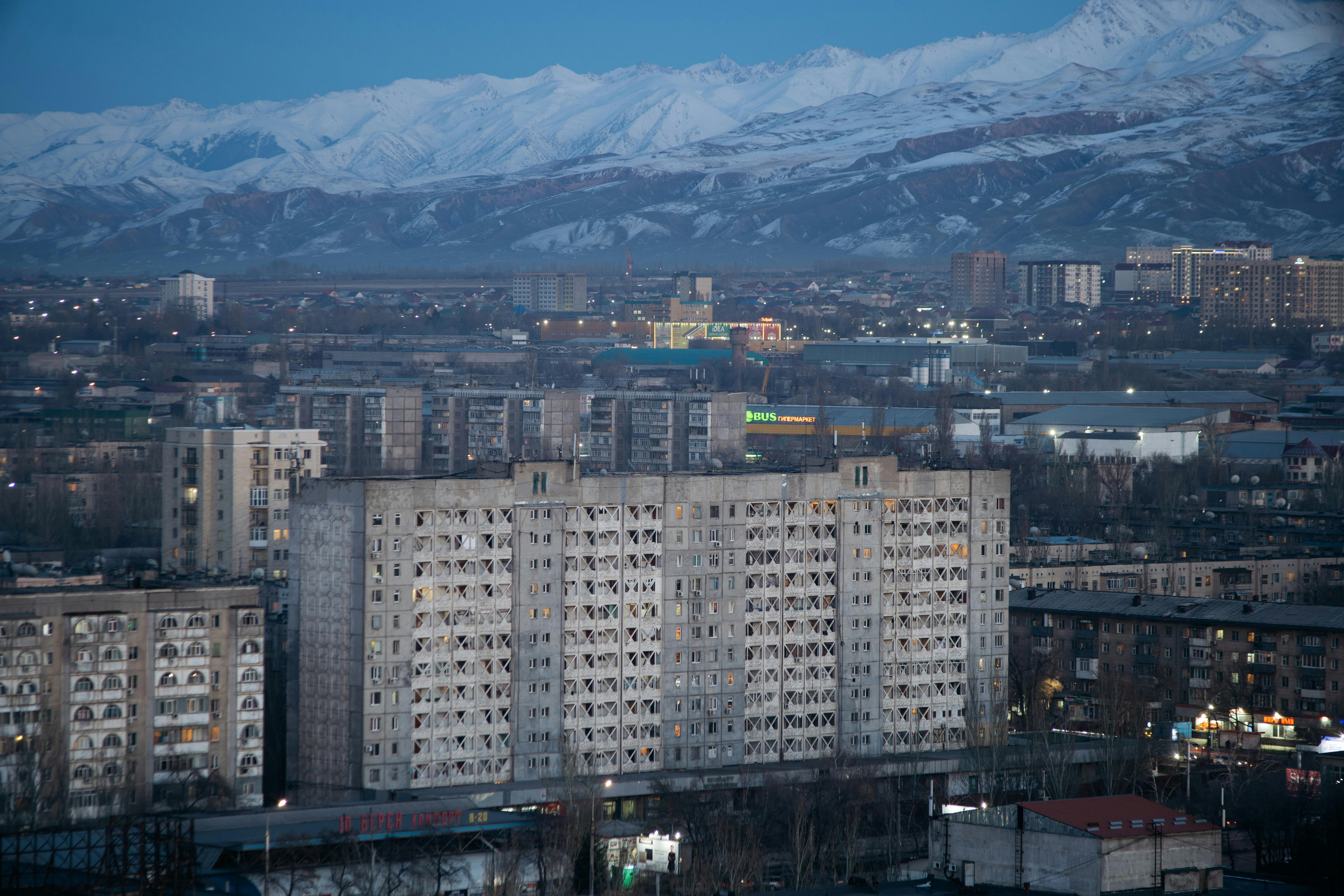 Bishkek cityscape at dusk with mountains, showcasing a blend of urban and natural beauty.
