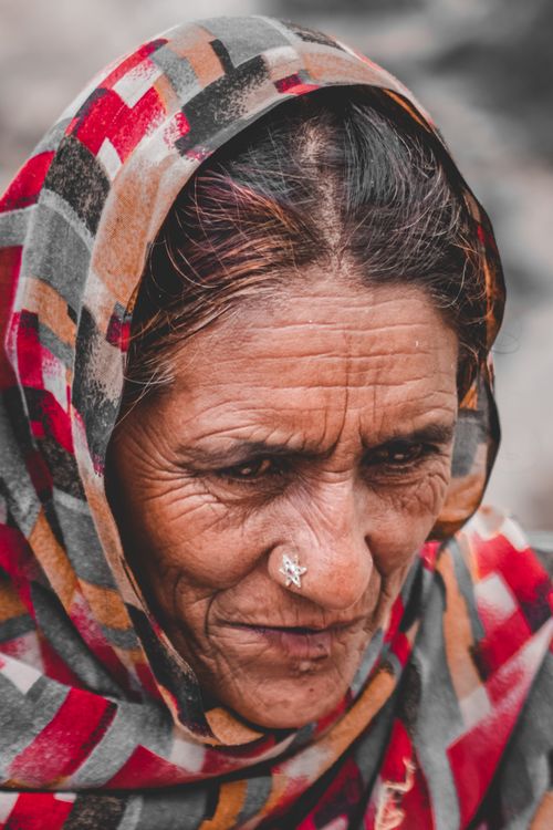 Free Close-up portrait of an elderly woman with a nose ring wearing a vibrant patterned hijab. Stock Photo