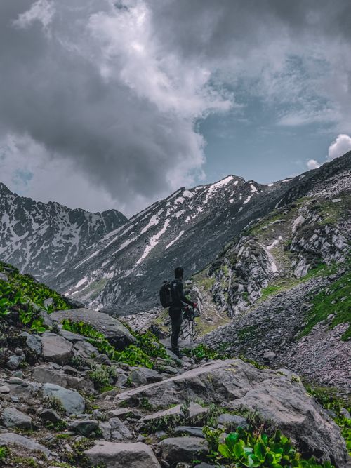 Free A lone hiker traverses a rugged mountain path under a dramatic sky, showcasing outdoor adventure. Stock Photo
