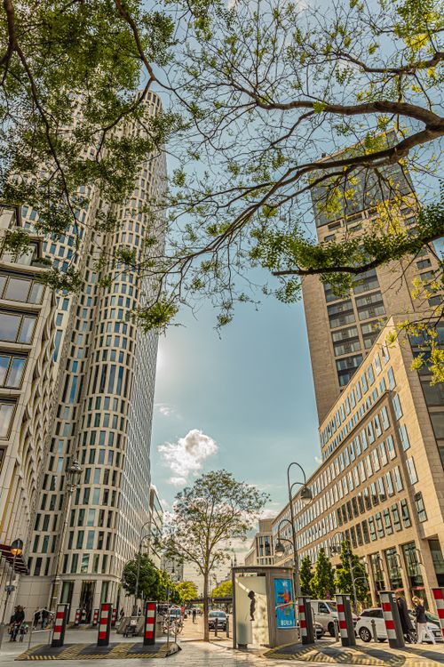 Free Street view of Berlin's modern skyscrapers with lush trees and clear skies. Stock Photo