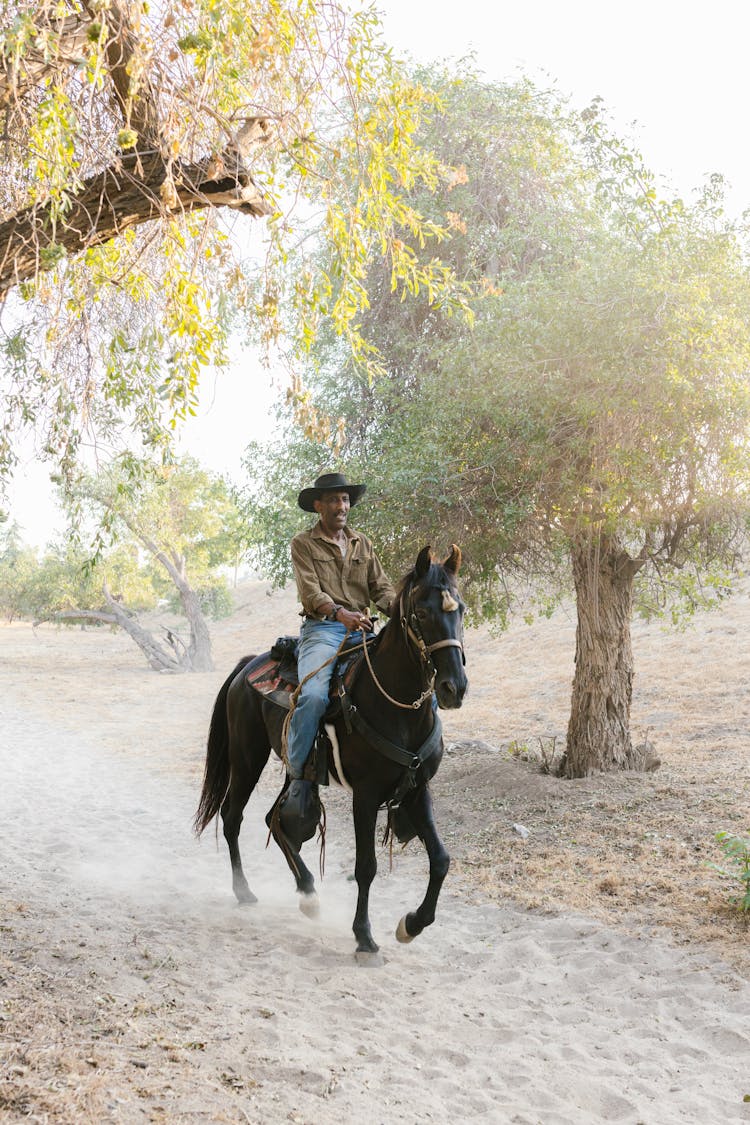 Man Riding Black Horse On Ranch