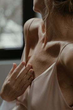 Artistic portrayal of a woman's collarbone and hand in soft lighting.