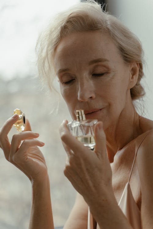 Free eldelry woman smelling a fragrant perfume stock photo