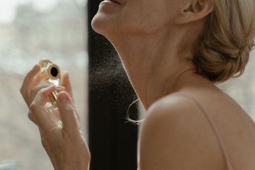 Free Close-up of a woman applying perfume with a glass bottle in natural light. Stock Photo