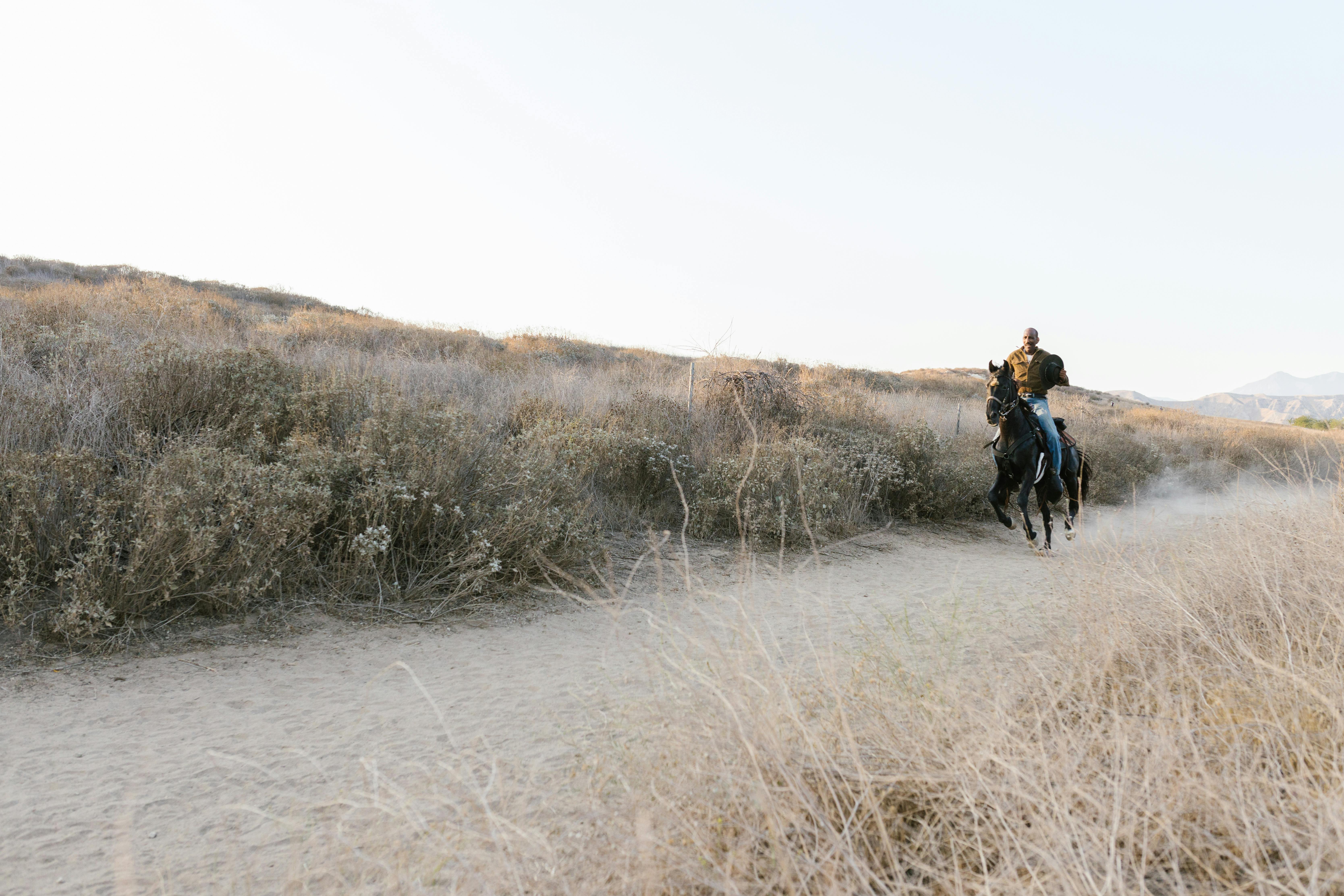 a man riding a horse on a dirt road