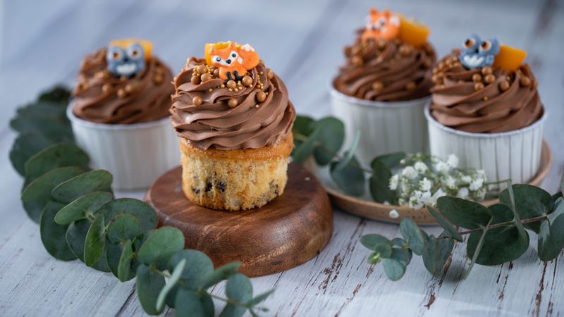 Delightful cupcakes topped with chocolate icing and animal figures, perfect for parties.