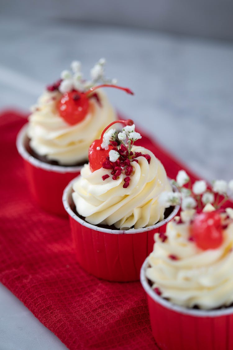 Red Cupcakes With Creamy Frosting And Cherry On Top