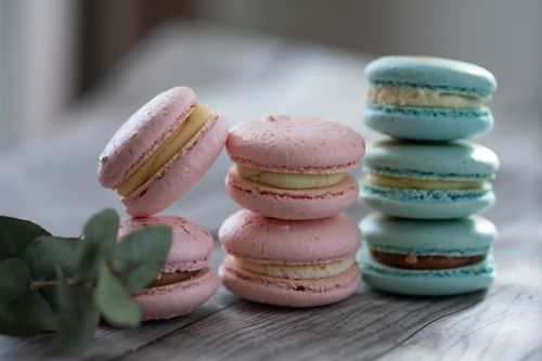 Free Close-up of pastel pink and blue macarons stacked on a rustic table. Stock Photo