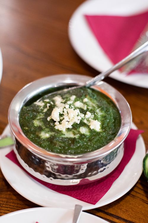 Palak paneer in a copper serving bowl topped with crumbled paneer