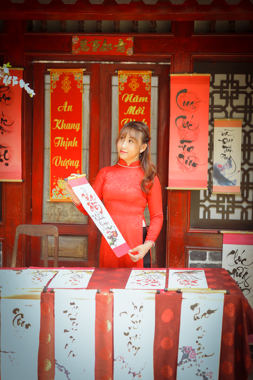 Free Woman in red dress at a traditional Chinese New Year market stall with calligraphy scrolls. Stock Photo
