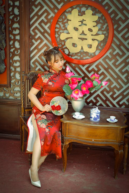 
A Woman in a Traditional Red Dress Looking at Flowers