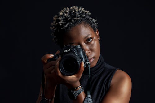 A Woman with Short Hair Holding a Digital Camera on Black Background