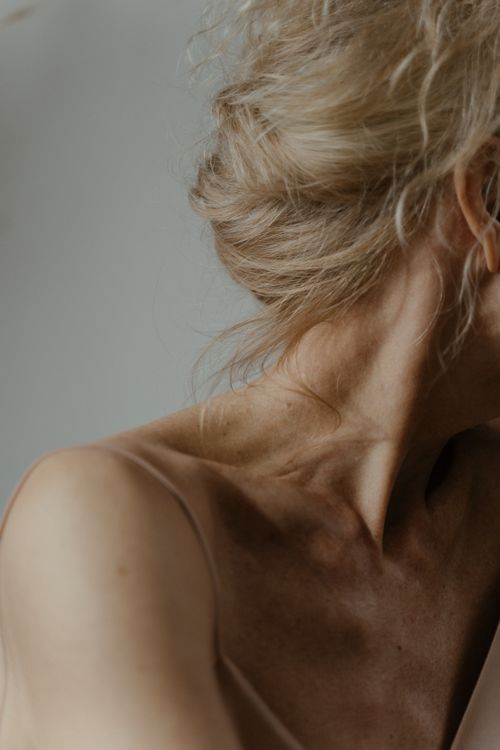 Free Artistic close-up portrait highlighting the neck and shoulder of a senior woman with a serene pose. Stock Photo