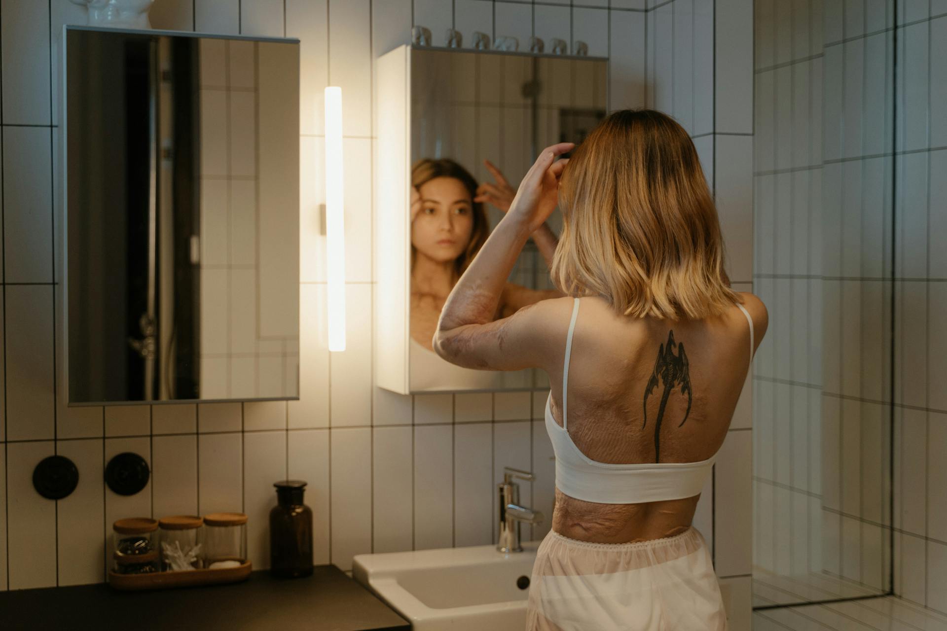 A Tattooed Woman with Burn Scars Looking at a Mirror