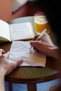 Person Holding Pen Writing on White Paper