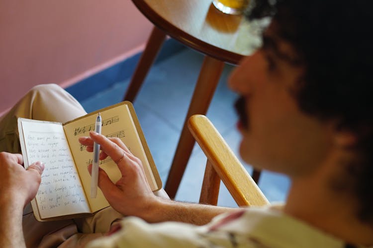 
A Man With A Mustache Holding A Pen And A Notebook