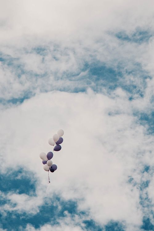 Free White and purple balloons ascending towards the clouds on a sunny day. Stock Photo