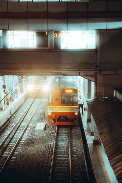 Free Orange train at a bustling Jakarta station platform, showcasing urban transportation dynamics. Stock Photo