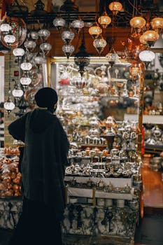 A woman explores a vibrant street market stall filled with traditional Turkish lamps and ceramics.
