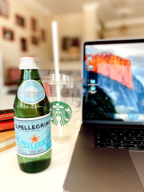 Bottle of Water, Drink in a Cup and a Laptop on a Cafe Table 