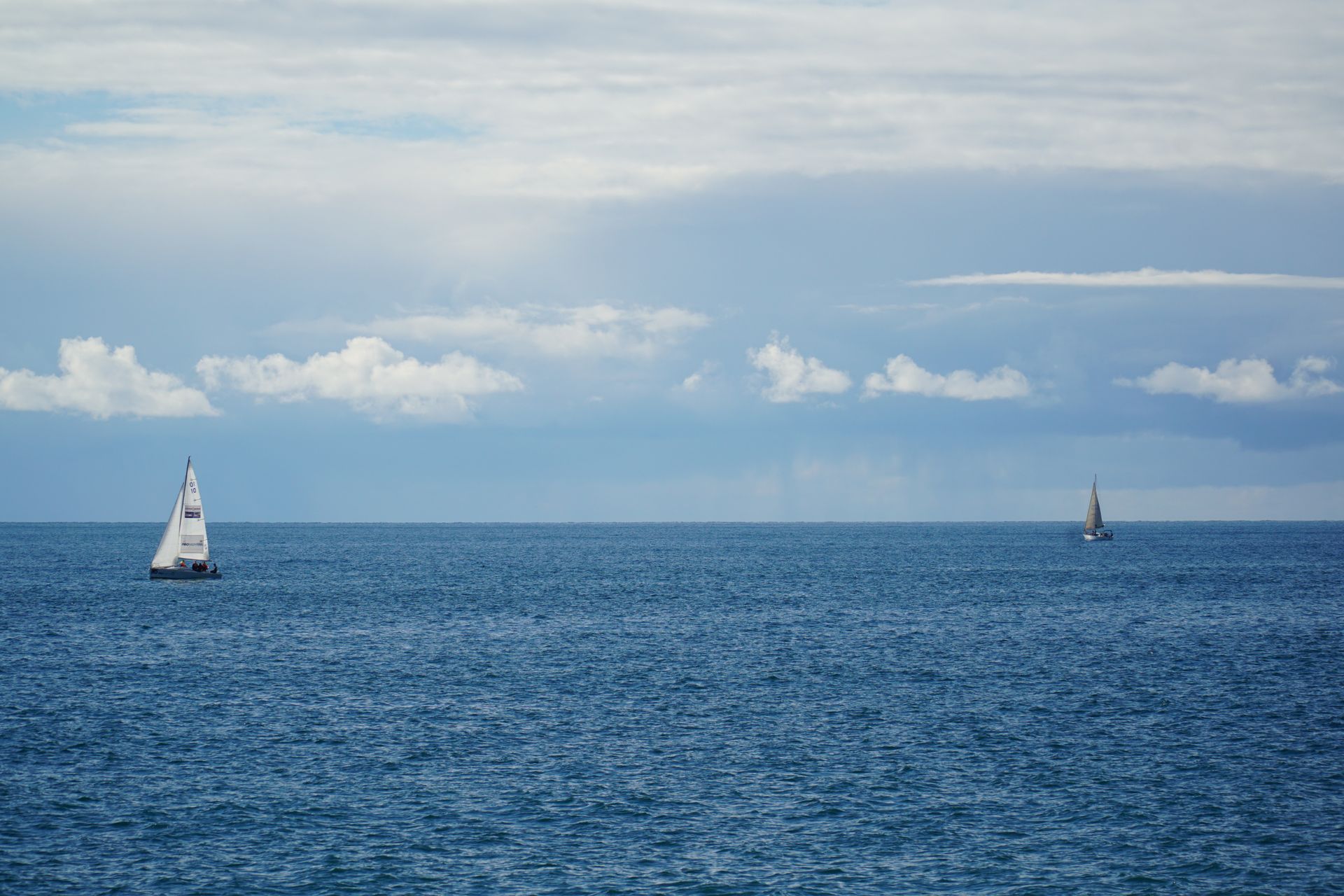 Two sailing boats on open water under a wide sky