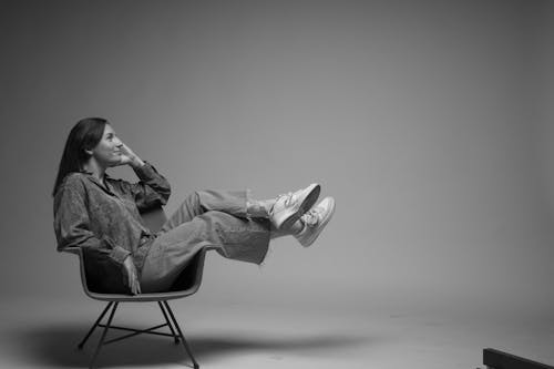 Free 
A Grayscale of a Woman Sitting on a Chair Stock Photo