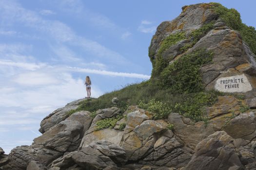 A Woman Standing on the Rocky Mountain with Grass