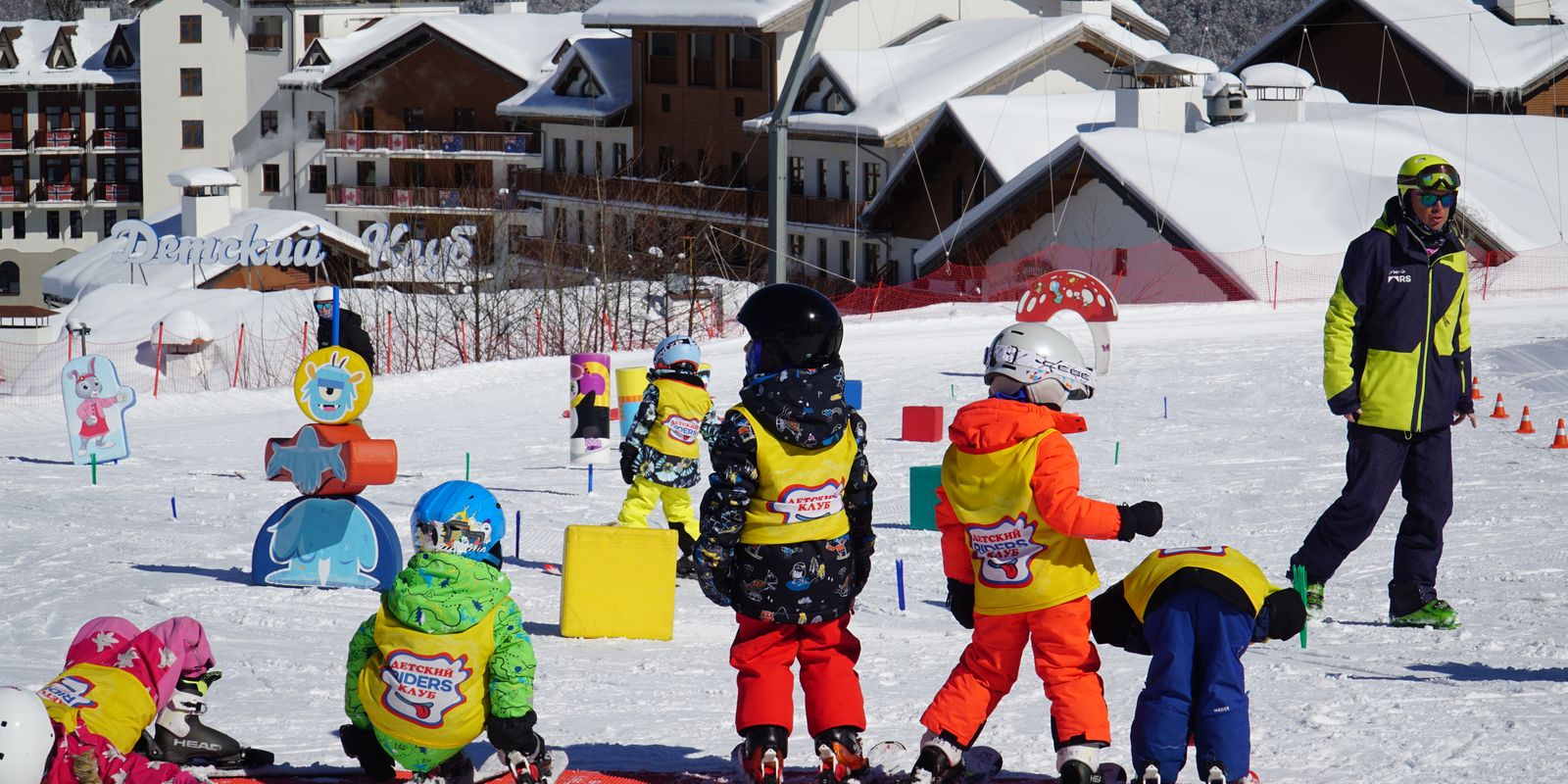 Children in colorful outfits enjoying a ski lesson on a snowy slope
