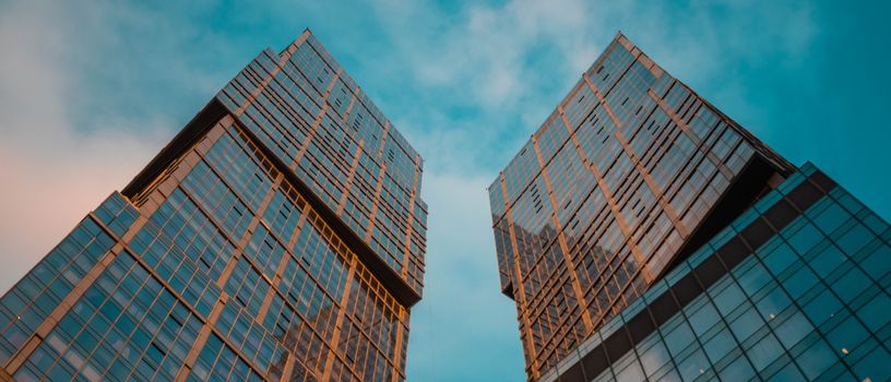 Low-angle shot of modern skyscrapers rising against a vibrant blue sky.