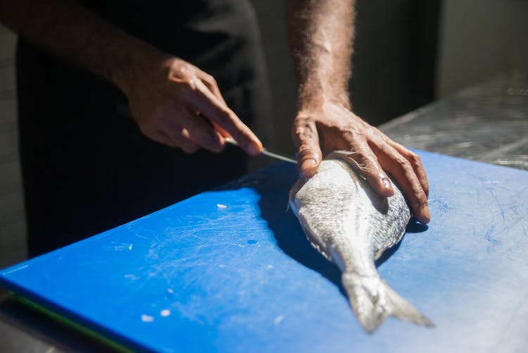 A Person Slicing A Fish