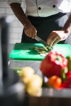 A chef expertly slices vegetables on a cutting board in a well-lit kitchen setting.