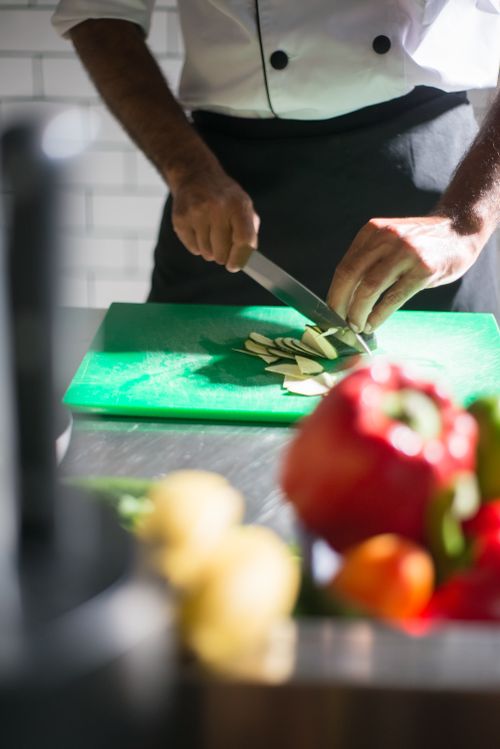 Free A chef expertly slices vegetables on a cutting board in a well-lit kitchen setting. Stock Photo