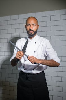 Chef in white uniform sharpening knife in a tiled kitchen setting, Portugal.
