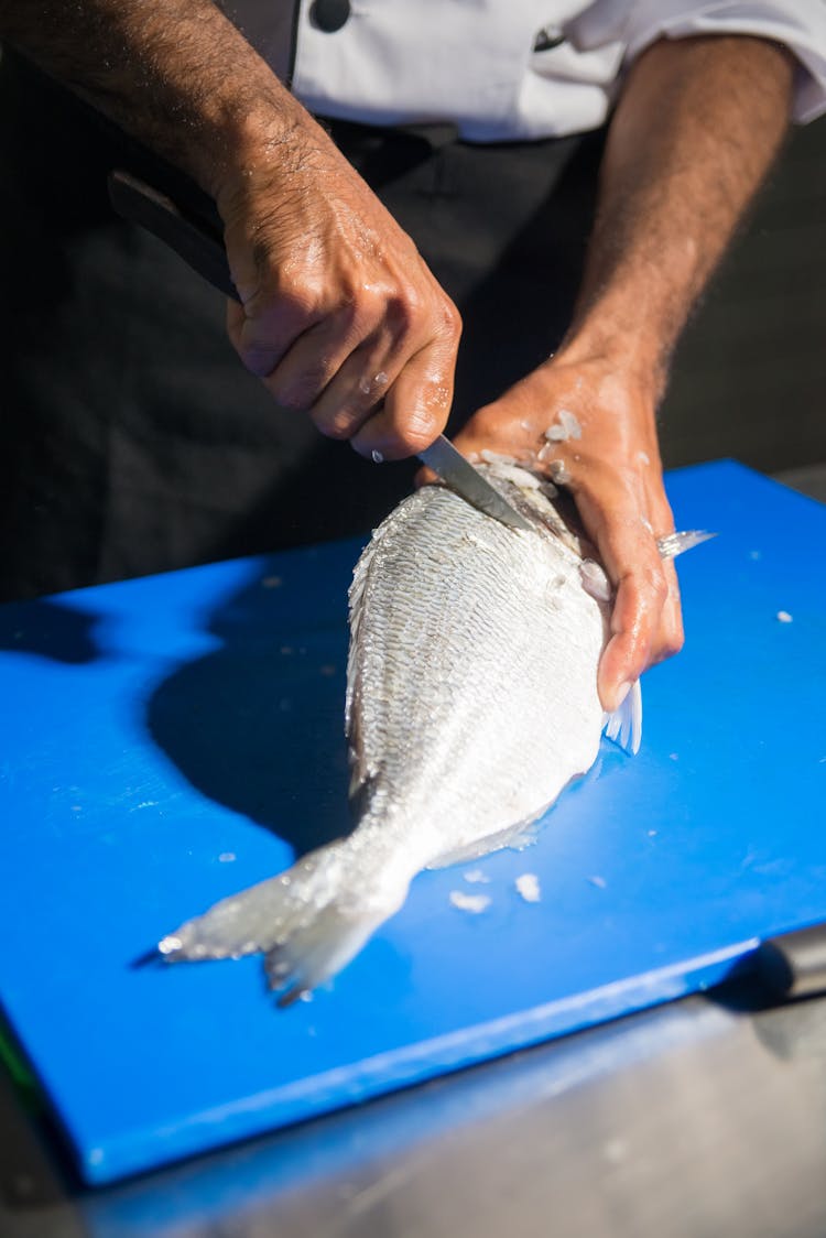 A Person Slicing A Fish