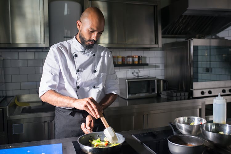 A Chef Cooking Fresh Vegetables On A Frying Pan