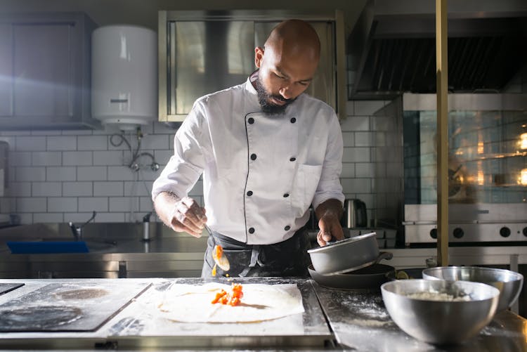 A Man In White Chef Uniform Cooking In The Kitchen