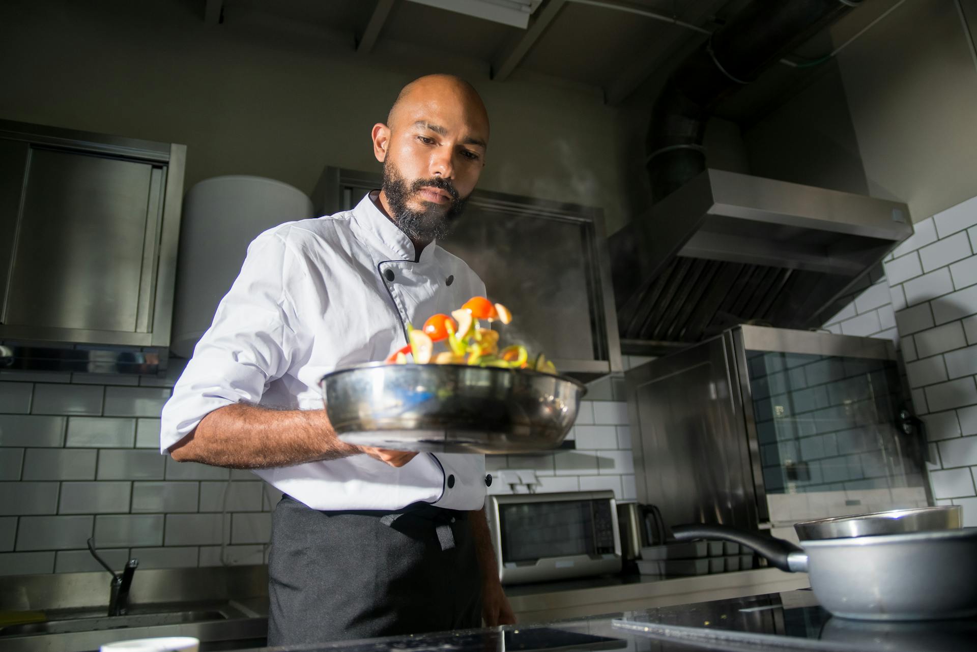 A skilled chef preparing a dish in a modern restaurant kitchen.