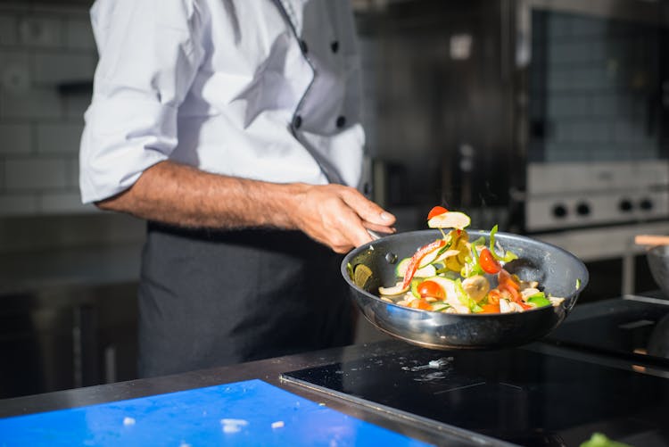 Chef Cooking Fresh Vegetables On A Frying Pan