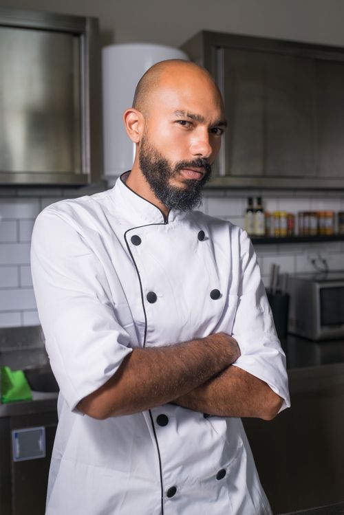 Free Portrait of a professional chef standing confidently in a modern kitchen setting. Stock Photo
