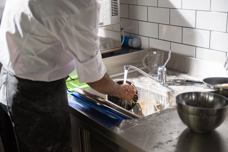 A Person Washing Dishes In The Sink