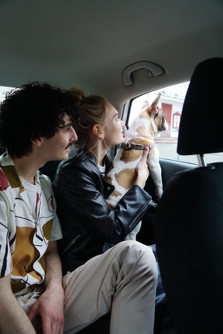 Couple Sitting At The Backseat Of A Car With Dog