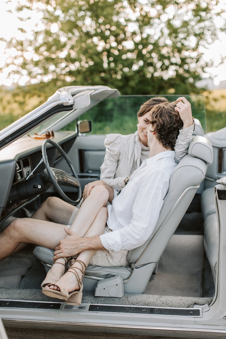 A Woman Sitting On The Man's Lap While In The Car