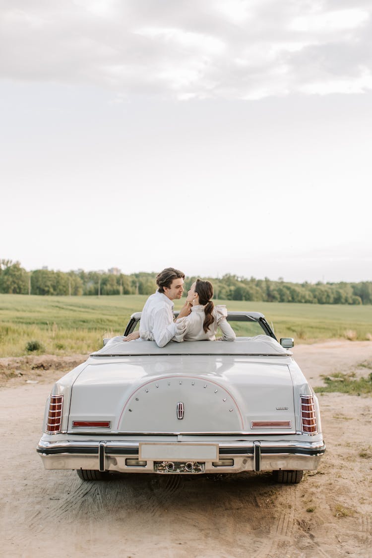 A Romantic Couple Kissing On The Car