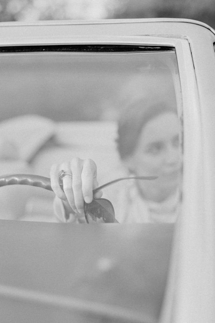 Grayscale Photo Of A Woman Driving A Car