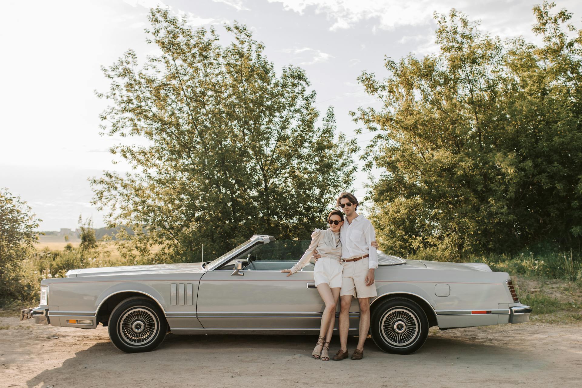 A Couple Standing Near the Convertible Car on the Unpaved Road