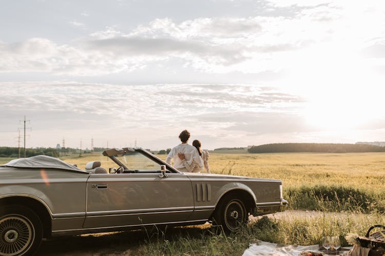 A Romantic Couple Sitting On A Car