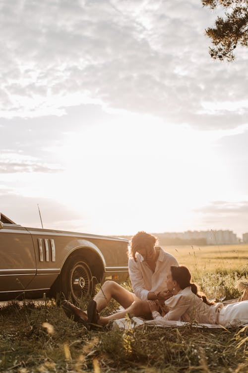 Free A Romantic Couple Sitting on a Grassy Field Stock Photo